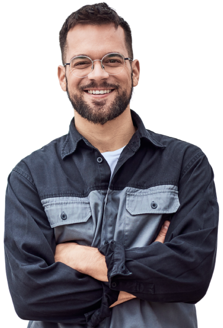 Um homem sorridente de barba e óculos, usando uma camisa de manga longa preta e cinza, de braços cruzados.