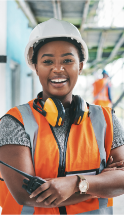 Três fotos de trabalhadores da construção civil usando equipamentos de segurança. A primeira imagem mostra uma mulher sorridente com capacete e colete refletivo, segurando um walkie-talkie. A segunda imagem mostra um grupo de trabalhadores discutindo com capacetes e coletes refletivos. A terceira imagem mostra um homem sorridente com óculos de segurança e colete refletivo, segurando um nível de bolha.